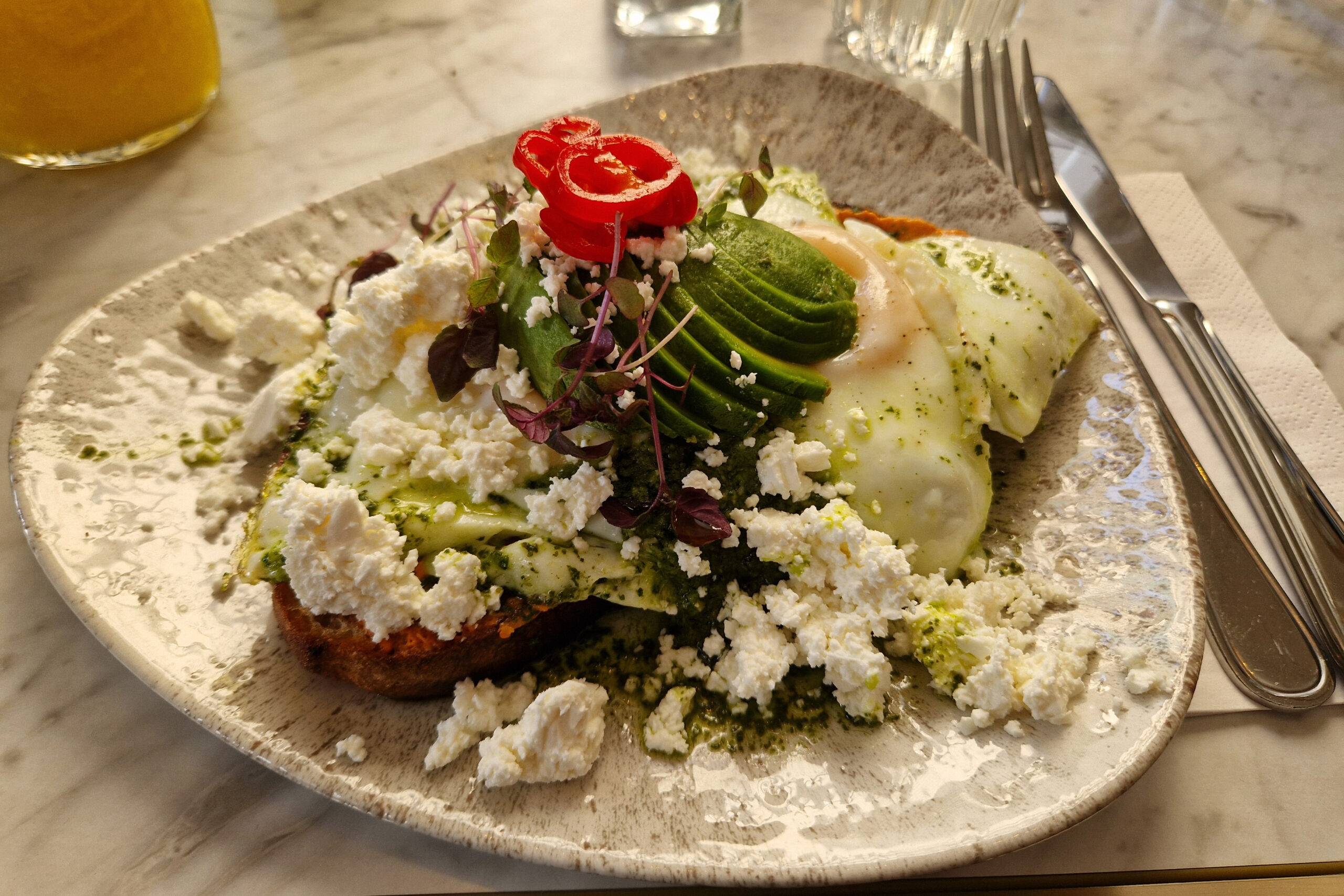 Fried eggs and sliced avocado on plate on table. Lunch at STHLM Brunch Club in Stockholm Sweden.