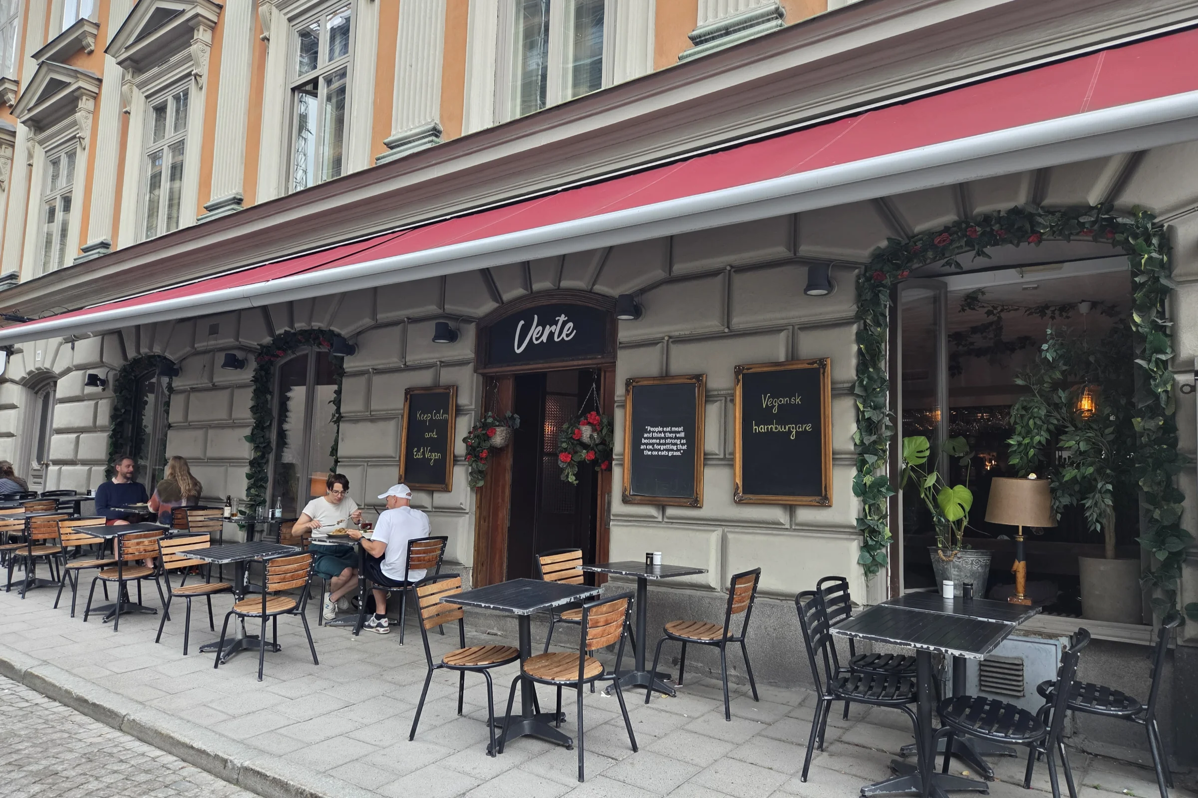 Restaurant Verte in Gamla Stan, Stockholm. Exterior view during the summer, with the outdoor tables and a few guests dining.