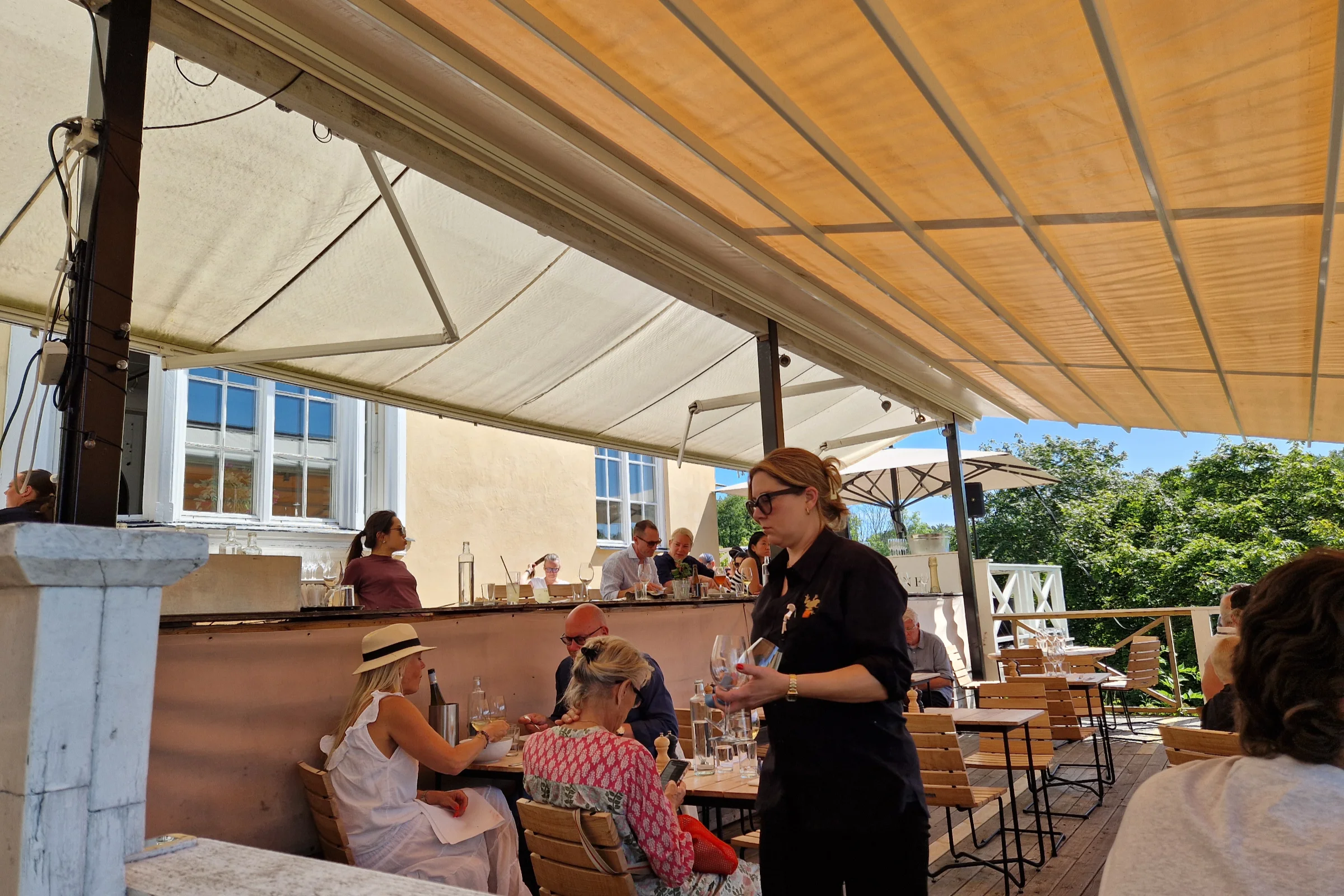 The outdoor veranda at Grinda Wärdshus, with lunch guests enjying their meal during a warm summer day in the Stockjolm archipelago.