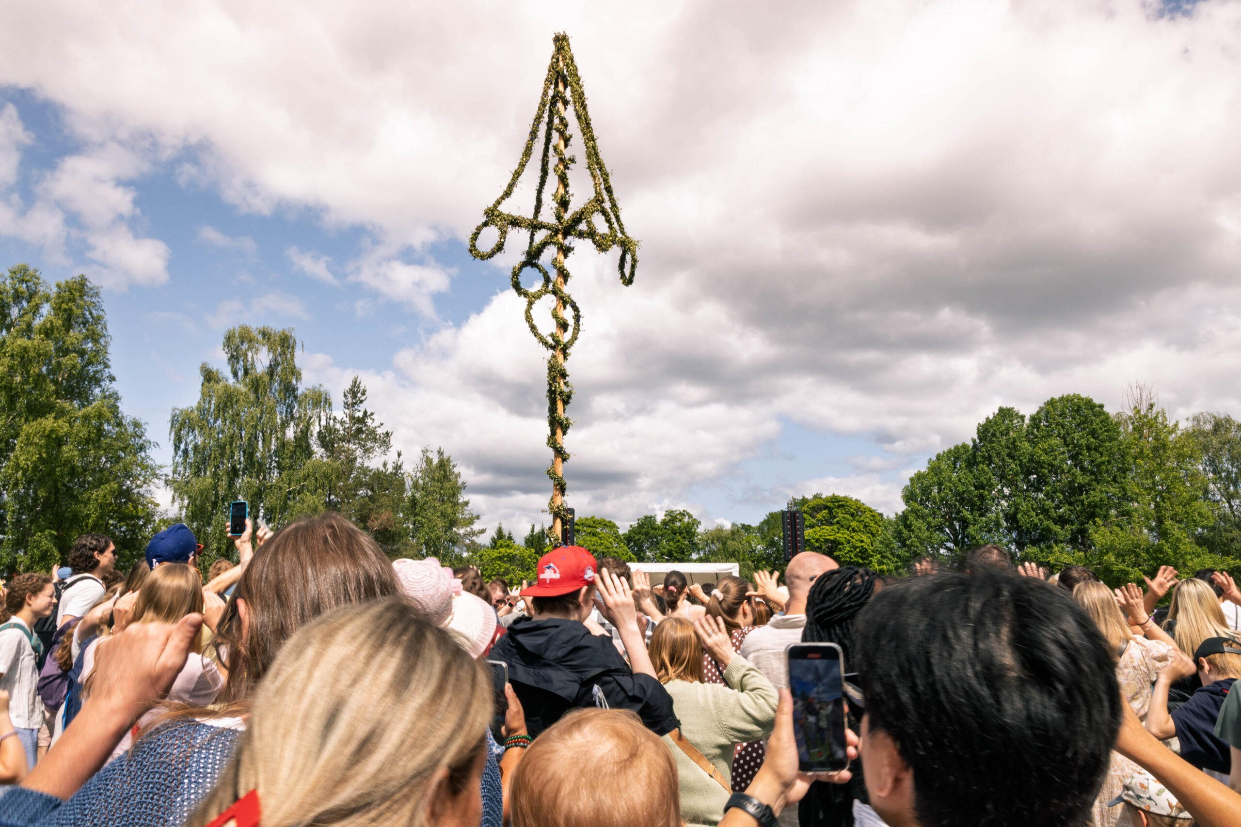 People dancing around Maypole (Midsommarstång) at Skansen in Stockholm, Sweden.