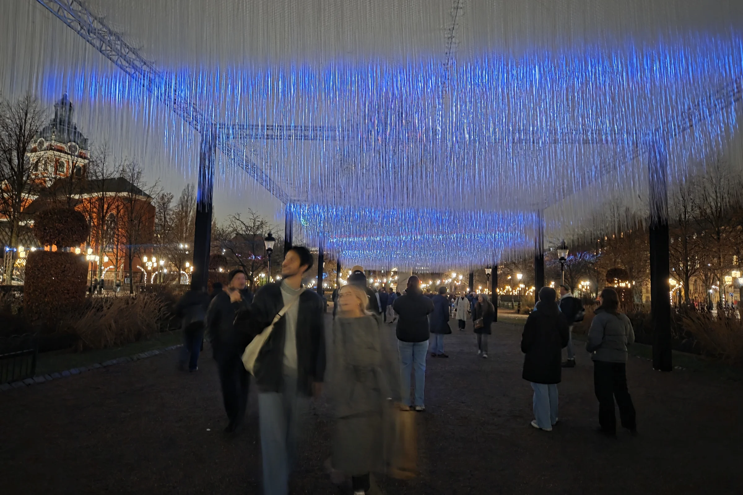 Nobel week lights in Kungsträdgården with people walking beneath a light installation.
