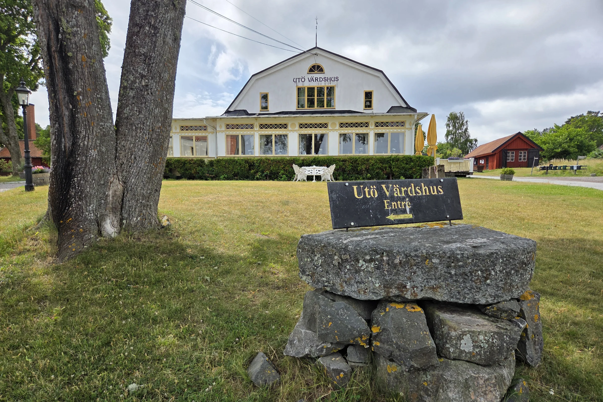 Utö Värdshus during a summer day viewed from outside with an entrance sign in the foreground.
